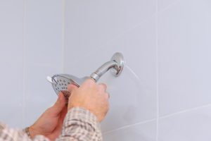 Workman repairing shower head in bathroom drops water on the shower