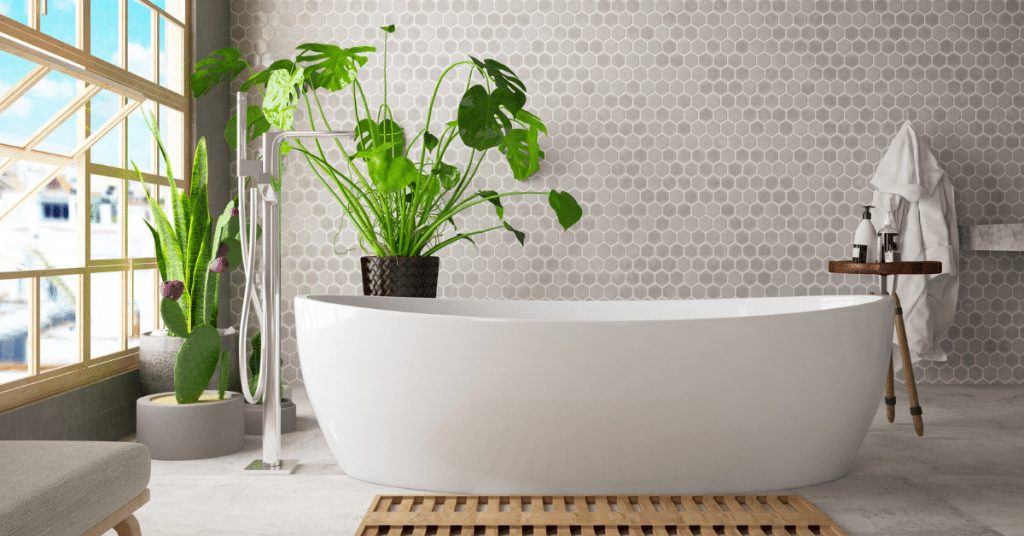 a bathroom with white bath a green plant and small tiles in the background